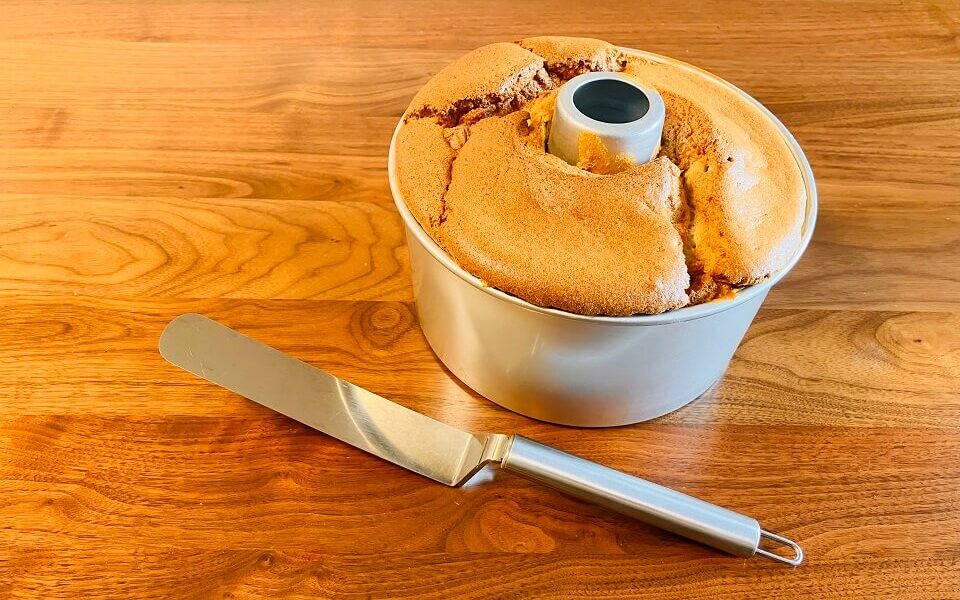 シフォンケーキ型の中に、焼きあがったシフォンケーキが入っている。近くにはパレットナイフが置かれている。